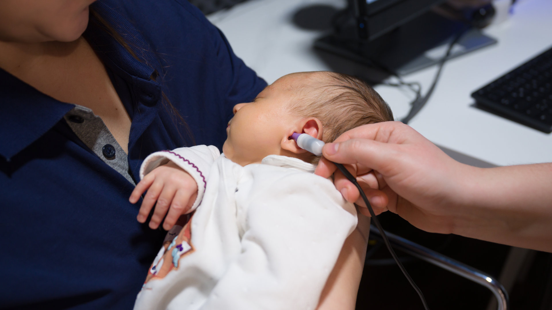 Nahaufnahme von einem Baby im Art der Ärztin, welches am Ohr untersucht wird